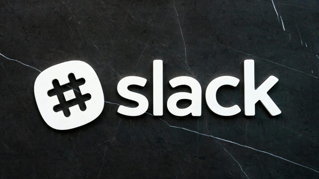 Close-up of Slack logo with hashtag symbol on a dark textured background, emphasizing digital communication.