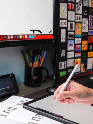 Close-up of a hand using a stylus on a tablet in a modern digital workspace.