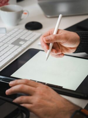 Designer working with a tablet and stylus in a modern workspace setup.