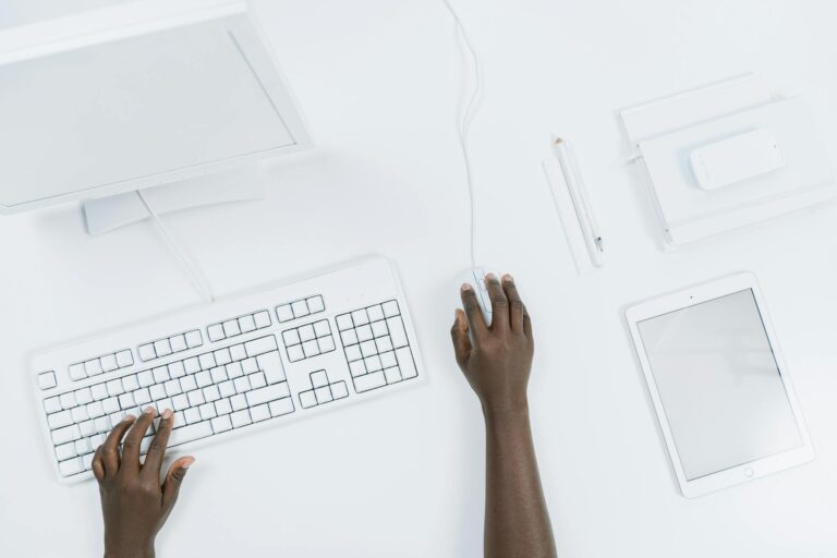 Top view of a minimalist workspace with a computer, keyboard, and tablet.